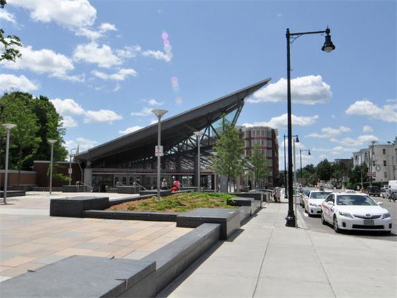 Front view of a modern building with a sloped roof and glass facade.
