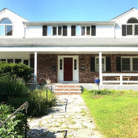 Front view of a two-story house with brick facade and red door.