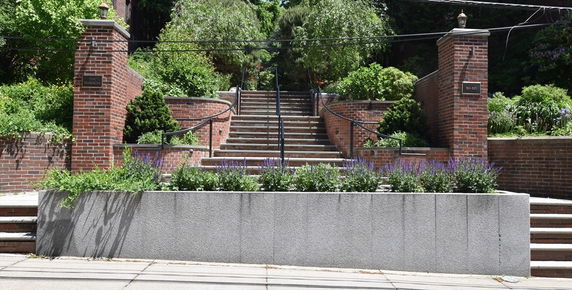 Front view of a building with brick pillars and a staircase leading to the entrance.