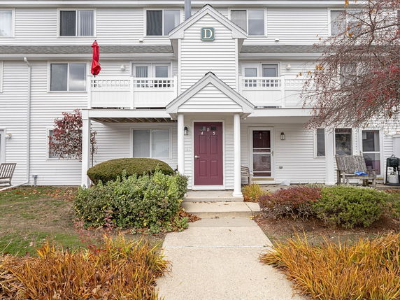 Front view of a multi-story residential building with white siding and balconies.