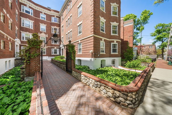 Front view of a multi-story brick building with decorative windows and a gated entrance.
