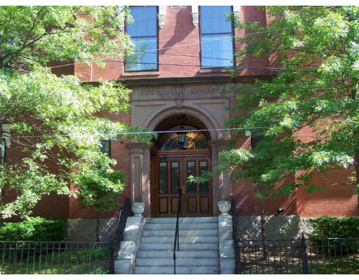 Front view of a brick building with a prominent entrance featuring steps and an archway.