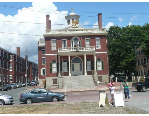 Front view of a historic multi-story brick building with a symmetrical facade, columns, and a dome on the rooftop.
