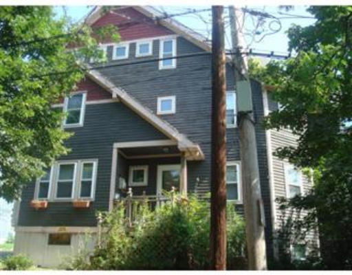 Front view of a three-story house with dark siding and a small porch.