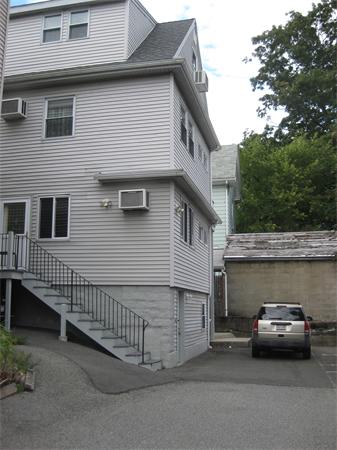Side view of a multi-story residential building with exterior staircase and parked vehicle.