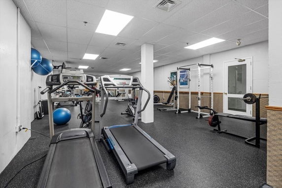Indoor gym area with treadmills, exercise equipment, and weights.