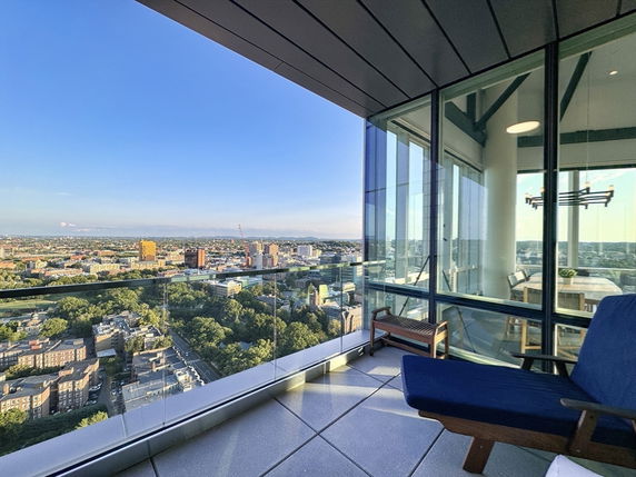 Panoramic view from a high-rise building balcony with cityscape.