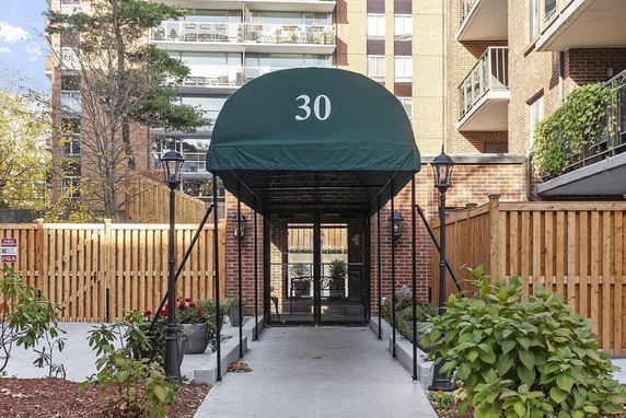 Front view of a building with a covered entrance and apartment balconies.