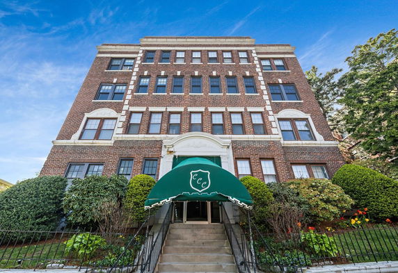 Front view of a multi-story brick building with a green awning above the entrance.