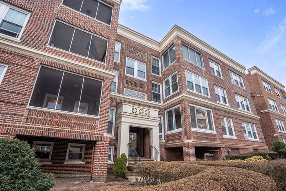 Front view of a multi-story brick apartment building with multiple windows and a central entrance.