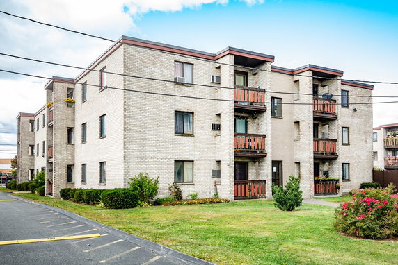 Front view of a three-story apartment building with balconies.
