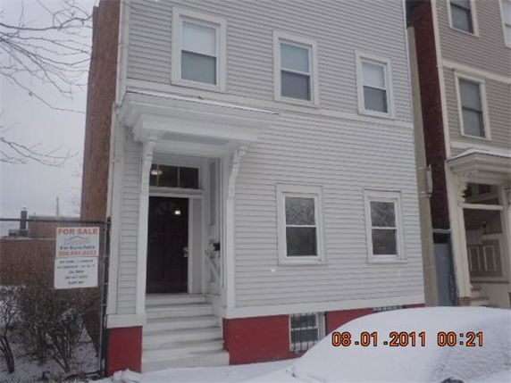 Front view of a three-story house with a porch and white siding.
