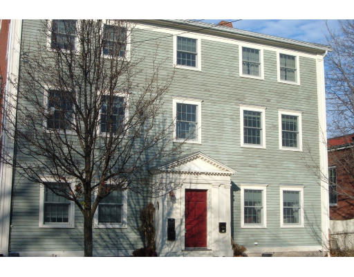 Front view of a multi-story house with a red door and multiple windows on the facade.