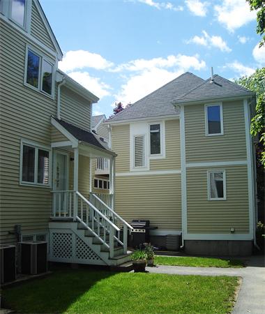 Front view of a multi-story house with beige siding and a small porch.