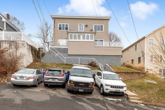 Front view of a multi-story house with a flat roof and large windows.