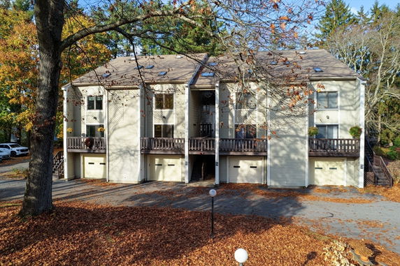 Front view of a multi-story residential building with multiple garage doors and balconies.