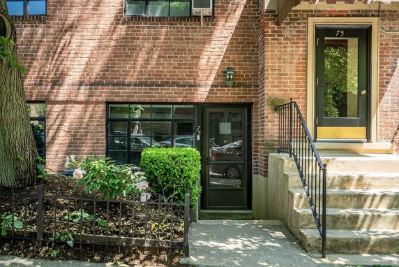 Front view of a brick building with stairs leading to an entrance door.