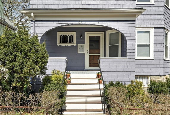 Front view of a house with a covered porch and steps leading to the entrance.