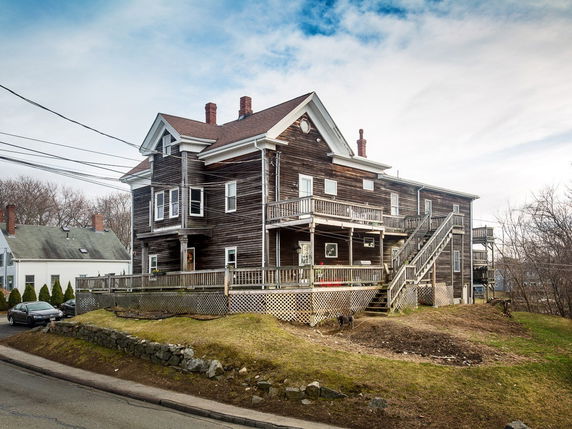 Front view of a multi-story wooden house with external stairs and a large porch.