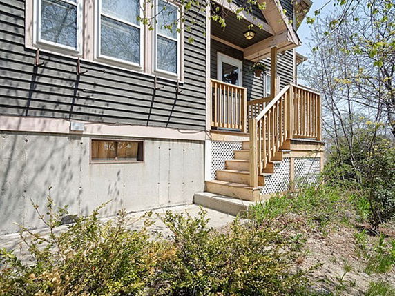 Front view of a house with a wooden porch and stairs.