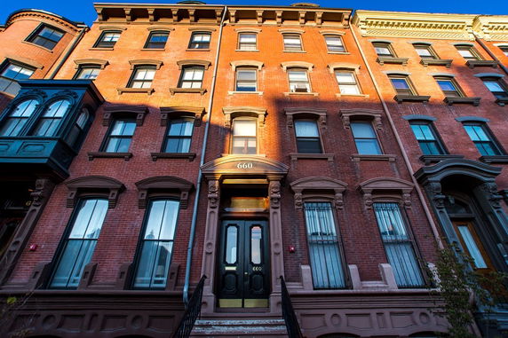 Front view of a multi-story brick building with tall windows and decorative architectural details.
