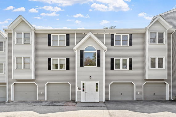 Front view of a multi-story house with three garage doors at the ground level.