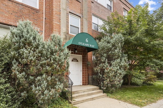 Front view of a brick apartment building with an entrance canopy labeled '6 O'Leary Way'.