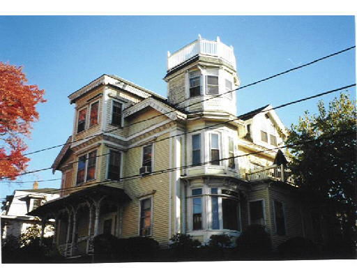 Front view of a multi-story house with a tower and decorative trim.