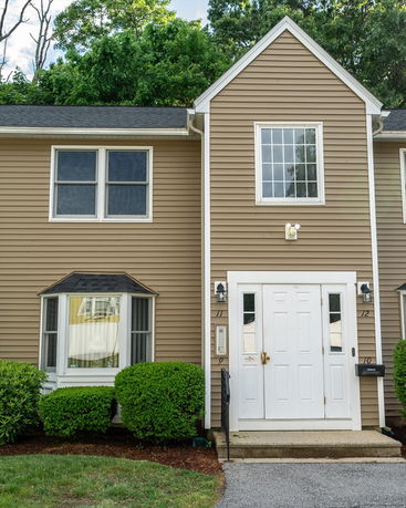Front view of a townhouse with brown siding and white trim.