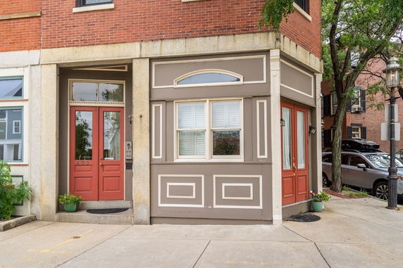 Front view of a two-story building with red doors and brick exterior.