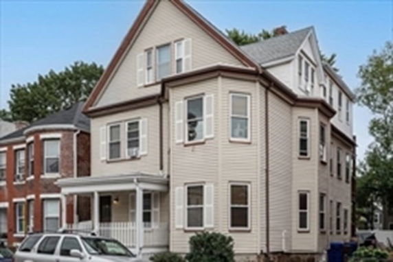 Front view of a multi-story house with a porch and gabled roof.