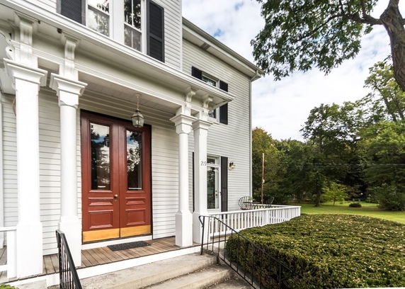 Front view of a two-story house with a red double front door and white columns.