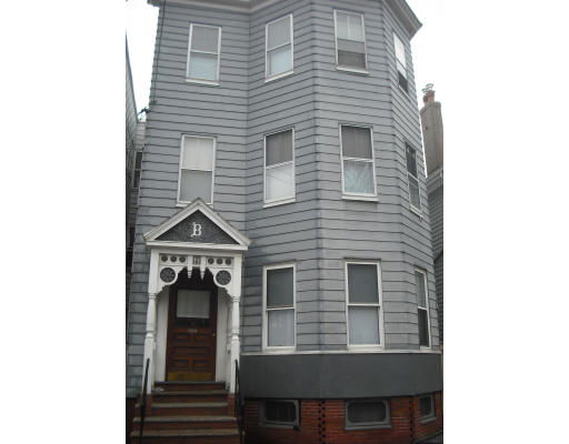 Front view of a three-story building with multiple windows and an entrance with decorative trim.
