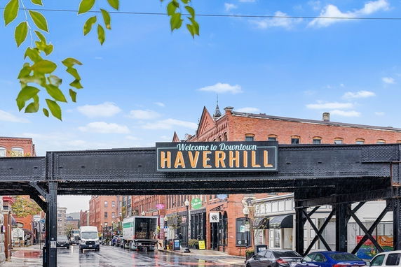 Street view of Haverhill with red brick buildings and an overhead sign welcoming to downtown.