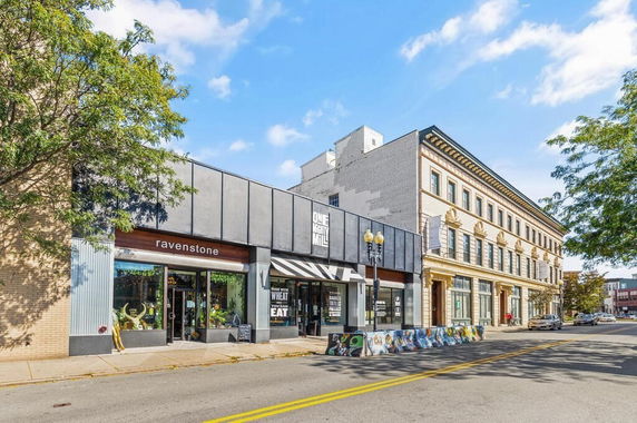 Front view of a commercial building with multiple storefronts in an urban area.