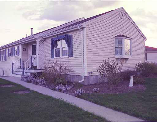 Front view of a single-story house with a porch and blue shutters.