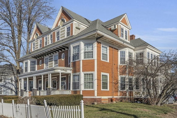 Front view of a large, two-story house with multiple gables and a porch.