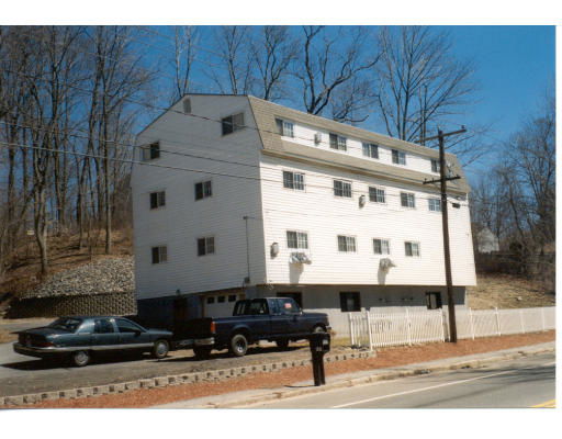 Front view of a multi-story building with a sloped roof and numerous windows.