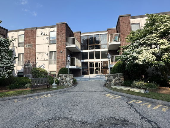 Front view of a multi-story apartment building with balconies and a central entrance.