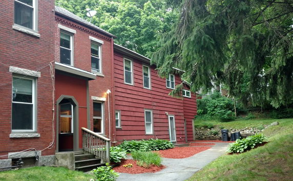 Front view of a two-story house with a mix of brick and red siding exterior.