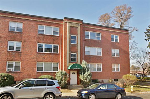 Front view of a three-story brick apartment building with multiple windows.