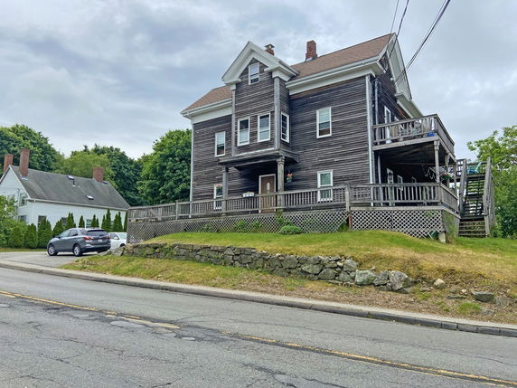 Front view of a multi-story house with wooden exterior and a large deck.