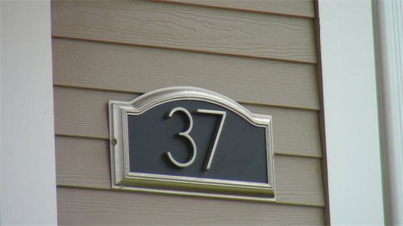 Exterior wall of a building featuring the number 37 on a plaque.