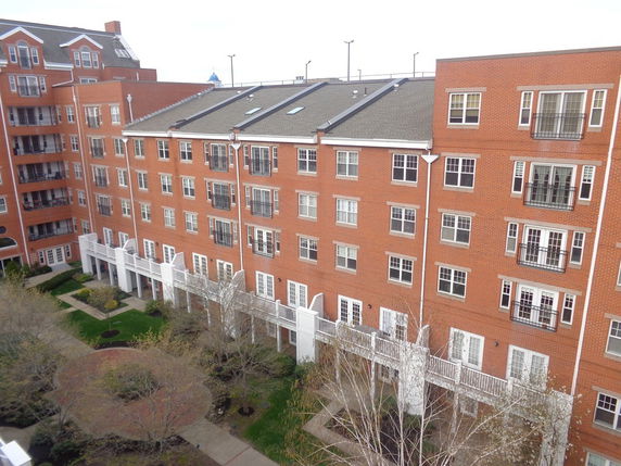 Front view of a multi-story brick apartment building with balconies and windows.
