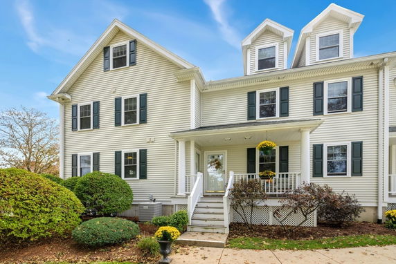 Front view of a multi-story house with white siding and black shutters.