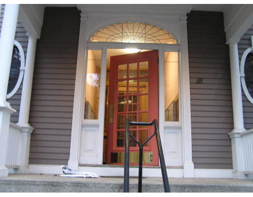 Front view of a house entrance with a red door and decorative columns.