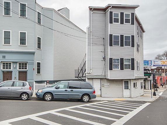 Front view of a narrow multi-story building on a street corner.