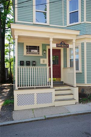 Front view of a two-story house with a small porch and red front door.