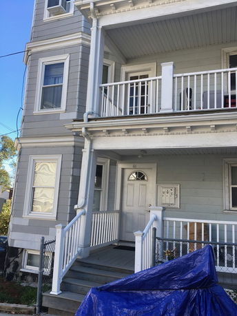 Front view of a multi-story house with a porch and balcony.
