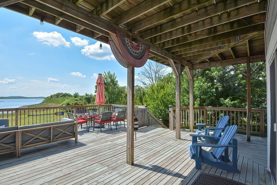 Wooden deck with chairs overlooking a scenic water view.